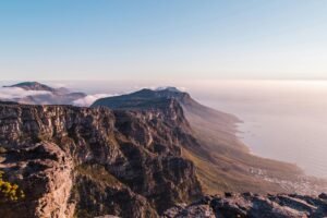 A stunning view of Table Mountain in Cape Town, showcasing dramatic cliffs and ocean at sunset.